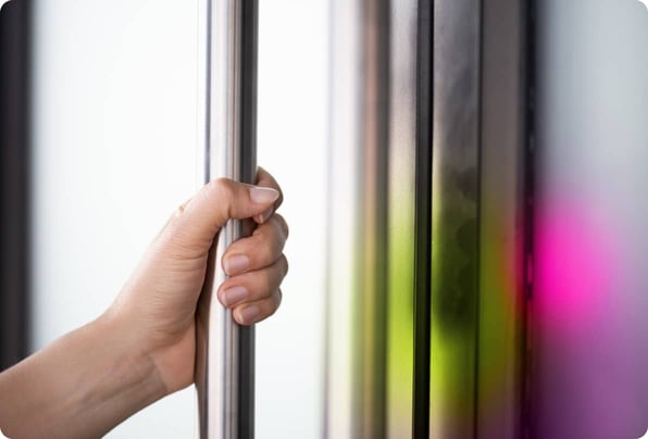 Close up of a hand gripping a typical metal office door handle