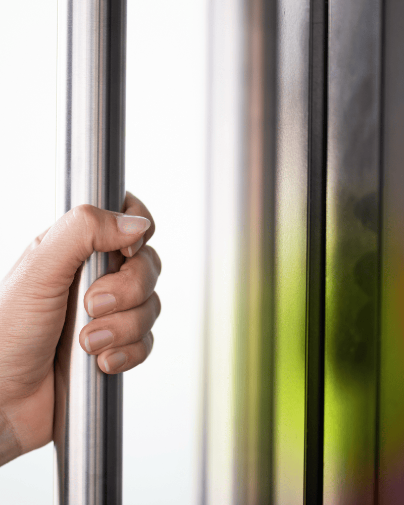 Close up of a hand gripping a typical metal office door handle